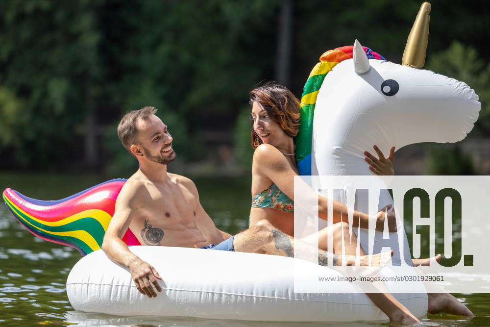 CREATIVE - Paar am See in Berlin Berlin, Deutschland - 25. Juli 2023: (CREATIVE) Ein Mann und eine Frau (Models) genießen auf einem aufgeblasenen Einhorn einen Sommertag an der Krummen Lanke, einem See in Berlin. Berlin