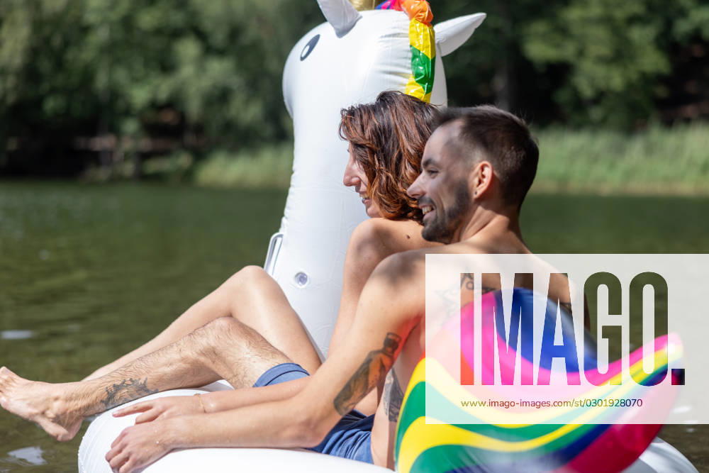 CREATIVE - Paar am See in Berlin Berlin, Deutschland - 25. Juli 2023: (CREATIVE) Ein Mann und eine Frau (Models) genießen auf einem aufgeblasenen Einhorn einen Sommertag an der Krummen Lanke, einem See in Berlin. Berlin
