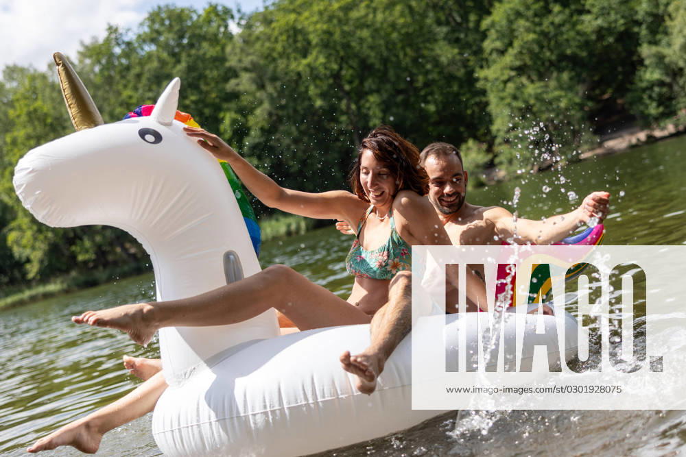 CREATIVE - Paar am See in Berlin Berlin, Deutschland - 25. Juli 2023: (CREATIVE) Ein Mann und eine Frau (Models) genießen auf einem aufgeblasenen Einhorn einen Sommertag an der Krummen Lanke, einem See in Berlin. Berlin
