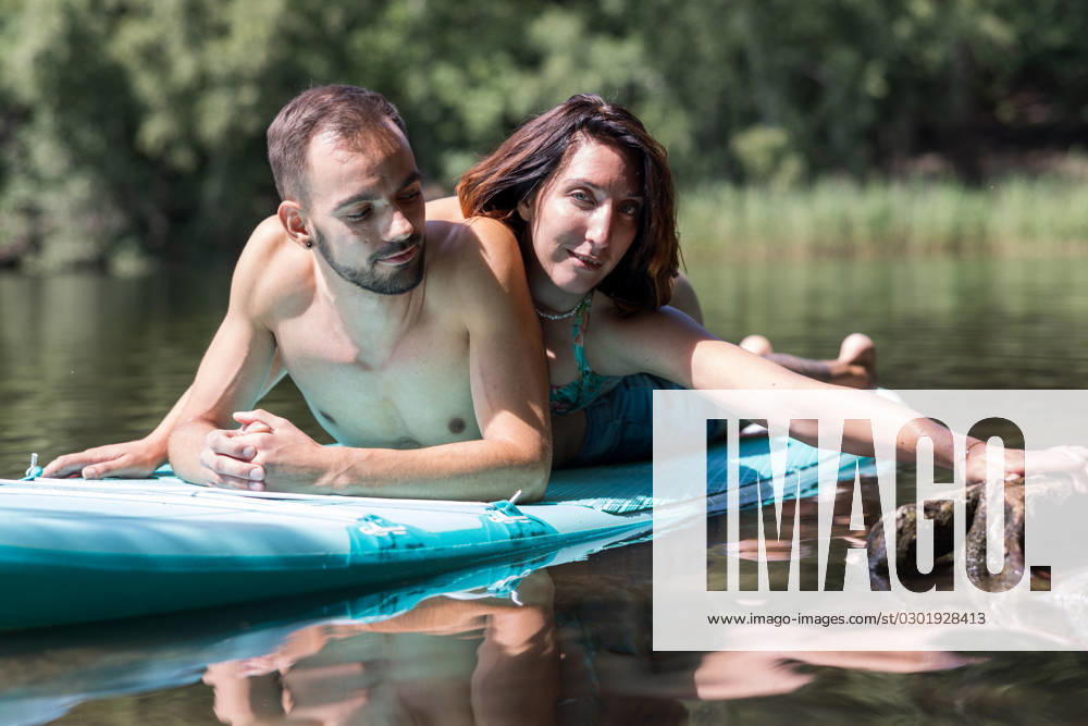 CREATIVE - Paar am See in Berlin Berlin, Deutschland - 25. Juli 2023: (CREATIVE) Ein Mann und eine Frau (Models) genießen auf einem SUP (stand up paddle boat) einen Sommertag an der Krummen Lanke, einem See in Berlin. Berlin
