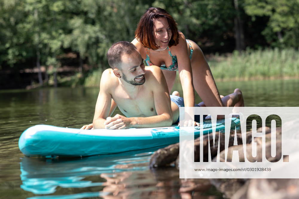 CREATIVE - Paar am See in Berlin Berlin, Deutschland - 25. Juli 2023: (CREATIVE) Ein Mann und eine Frau (Models) genießen auf einem SUP (stand up paddle boat) einen Sommertag an der Krummen Lanke, einem See in Berlin. Berlin