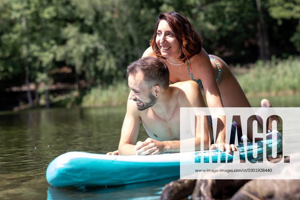 CREATIVE - Paar am See in Berlin Berlin, Deutschland - 25. Juli 2023: (CREATIVE) Ein Mann und eine Frau (Models) genießen auf einem SUP (stand up paddle boat) einen Sommertag an der Krummen Lanke, einem See in Berlin. Berlin