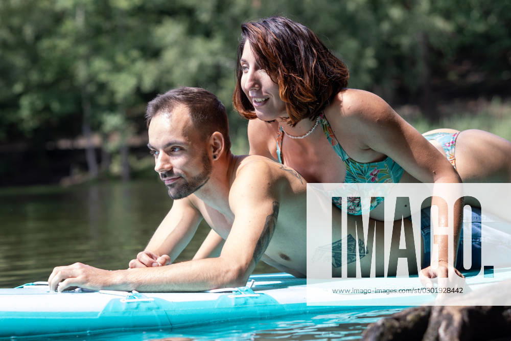CREATIVE - Paar am See in Berlin Berlin, Deutschland - 25. Juli 2023: (CREATIVE) Ein Mann und eine Frau (Models) genießen auf einem SUP (stand up paddle boat) einen Sommertag an der Krummen Lanke, einem See in Berlin. Berlin