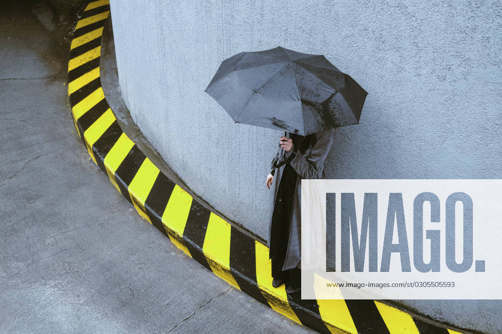 Woman holding umbrella standing near wall model released, Symbolfoto, YHF00093