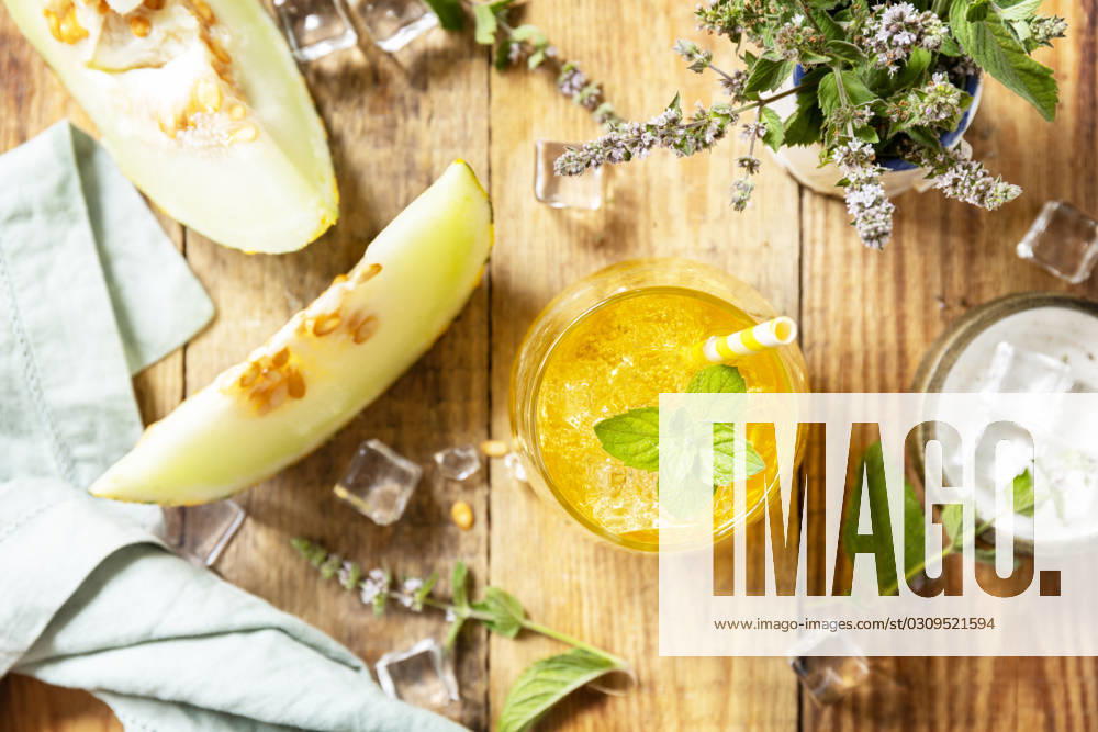 Fresh refreshing fruity summer drink, seasonal beverages. Melon lemonade in glasses with ice and mint on a wooden rustic table. View from above. Fresh refreshing fruity summer drink, seasonal beverages. Melon lemonade in glasses with ice and mint on a wooden rustic table. View from above.