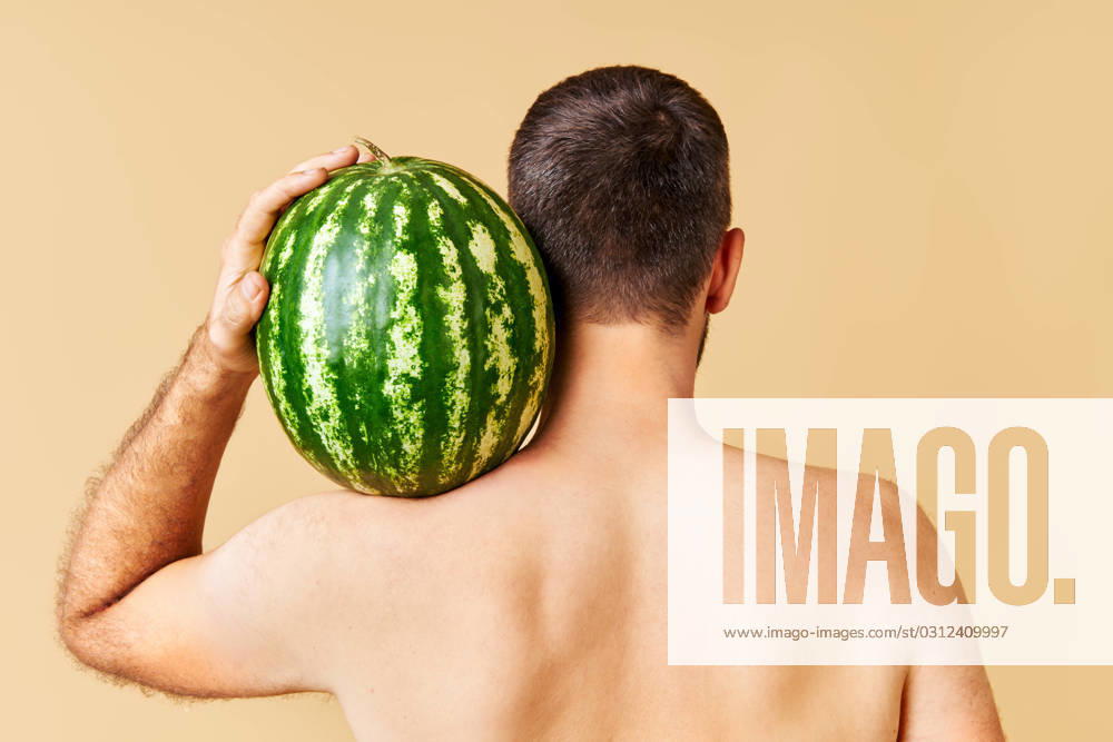 Back view of young man holding fresh watermelon on shoulder Back view of young man holding fresh watermelon on shoulder over light background ,model released, Symbolfoto