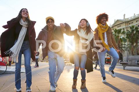 Group of multiracial friends having fun outdoors, walking holding hands and laughing at the city during winter time. group, people, young, happy, outdoor, student, life, team, fun, together, support, holiday, joy, school, couple, lifestyle, smile, beauty, freedom, row, season, cheerful, girl, hat, weekend, vacation, carefree, celebration, teenager, enjoyment, leisure, active, playful, friend, hold, hand, flare, walk, street, urban, gather, woman, man, city