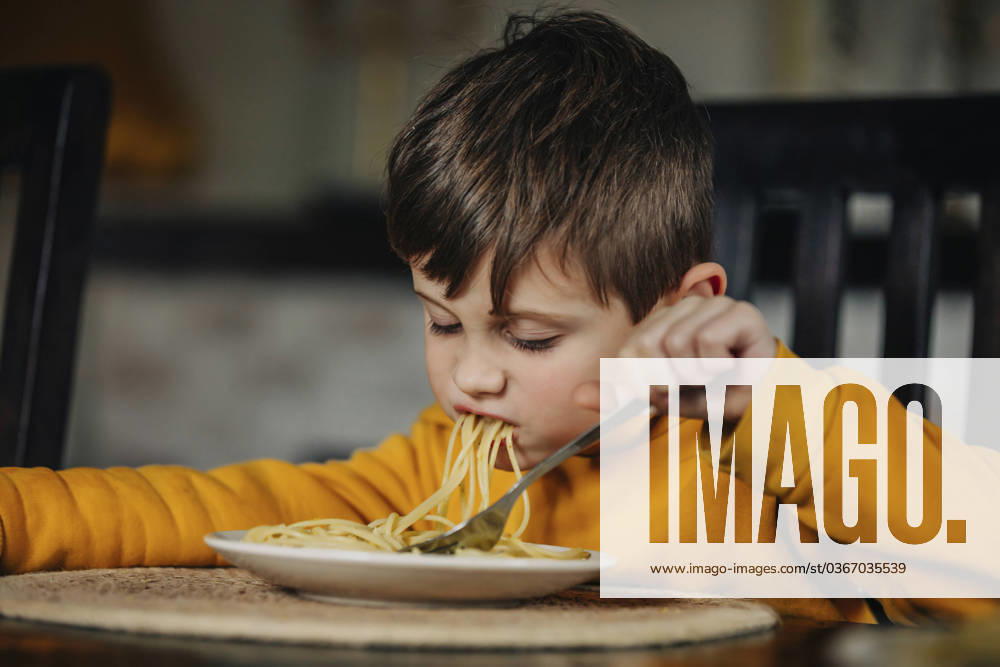 Hungry boy eating pasta at home model released, Symbolfoto, VSNF01415