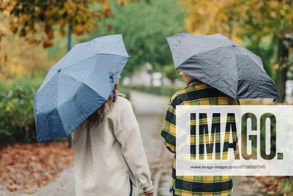Mother and daughter holding umbrellas and walking in autumn park model released, Symbolfoto, VSNF01472