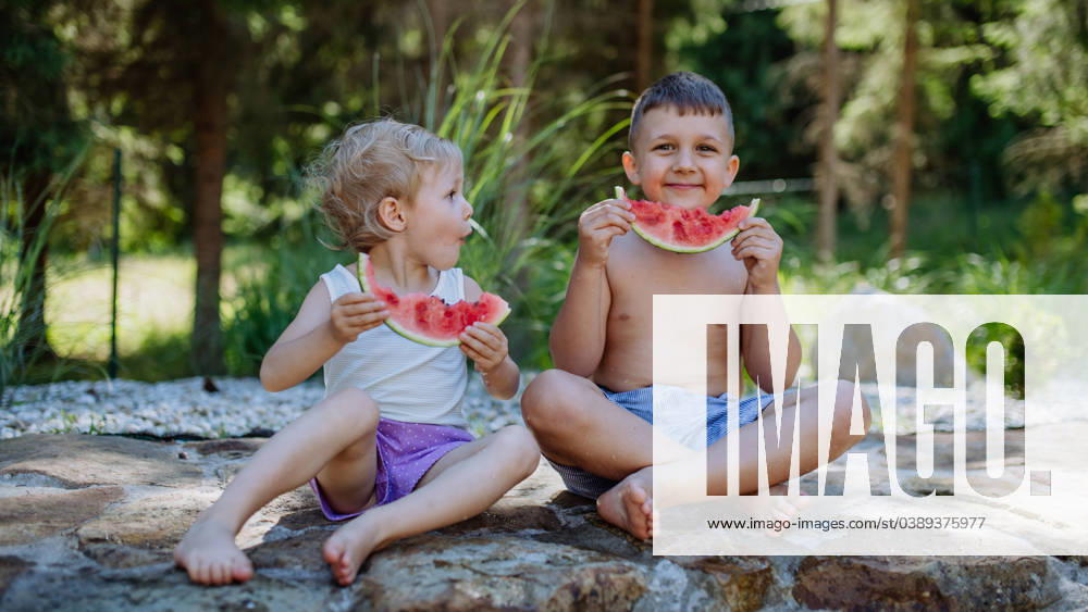 Little chidren sitting near lake and eating watermelon on hot sunny day during summer vacation. Little chidren sitting near a lake and eating watermelon on hot sunny day during summer vacation. model released
