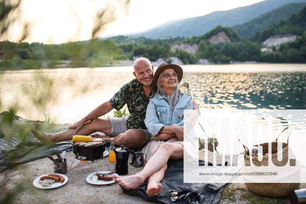 Happy senior couple resting on summer holiday trip, barbecue by lake. Portrait of happy senior couple resting on summer holiday trip, barbecue by lake. model released