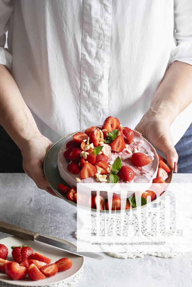 Hands of woman holding plate with ready-to-eat vegan strawberry tart model released, Symbolfoto, EVGF04457
