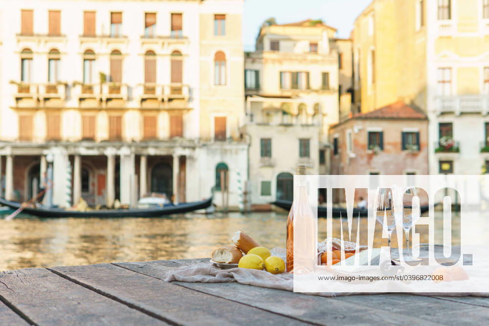 Rose wine, fruits and snacks on the wooden pier during picturesque picnic on the wooden dock Rose wine, fruits and snacks on the wooden pier during picturesque picnic on the wooden gondola dock