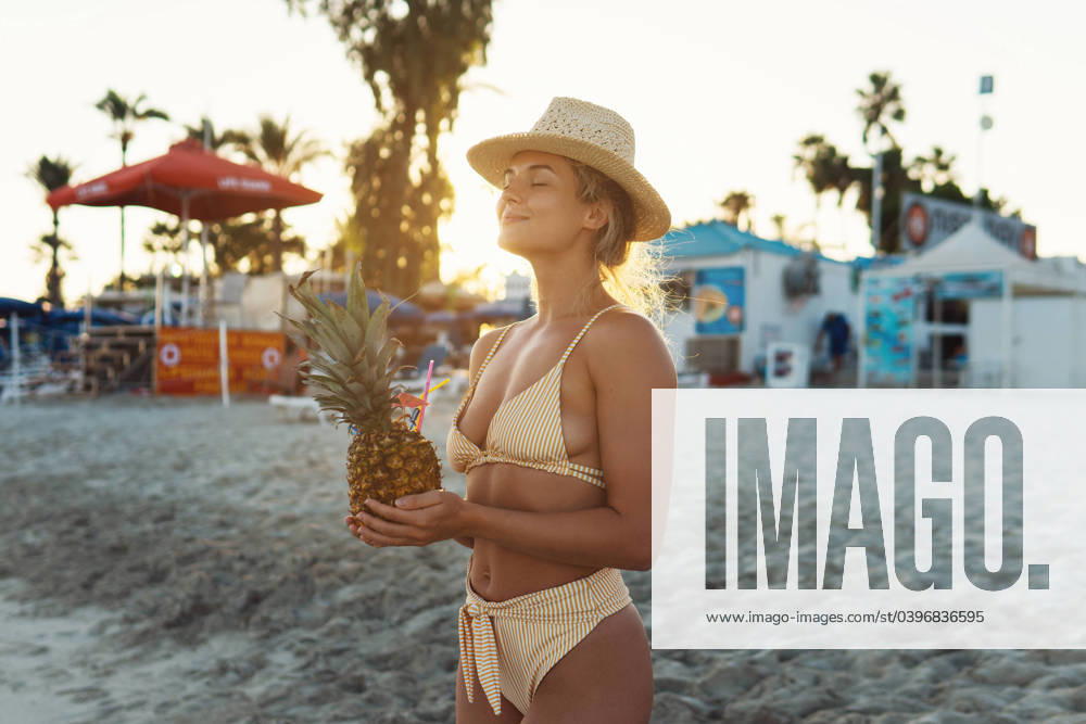 Young happy woman enjoying cocktail in pineapple during sunset on the beach Young happy woman enjoying cocktail in pineapple during sunset on the beach. ,model released, Symbolfoto