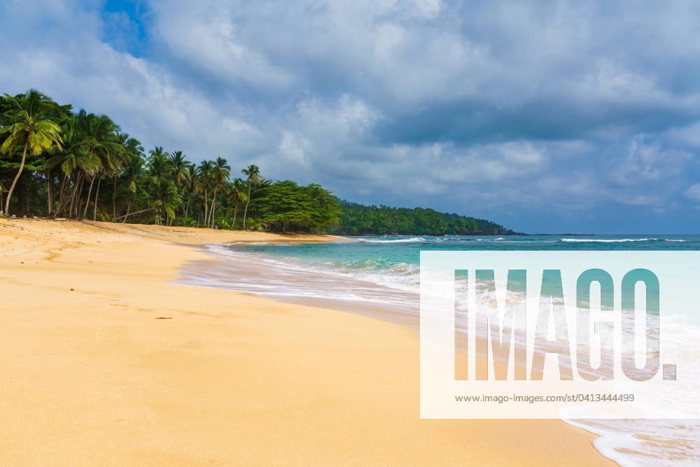 Tranquil sandy shore of Praia Emilia with gentle waves and tropical palms under a cloud-filled sky, encapsulating paradise. Model Released AddventurePhoto_ID19103_568061_027