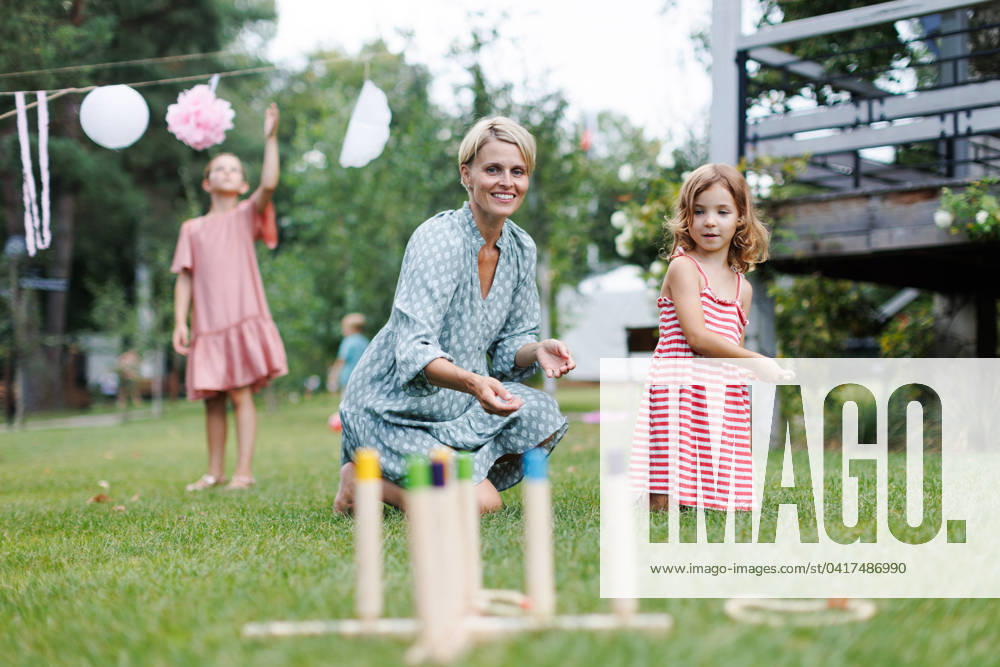 Woman playing with girl in the garden, outdoor garden games, sitting on grass. Woman playing with daughtere in the garden, outdoor garden games, sitting on grass. model released