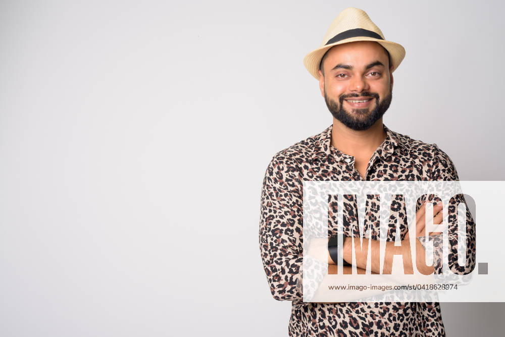 Portrait of happy young bearded Indian man smiling with arms crossed Studio shot of young handsome bearded Indian man against white background ,model released, Symbolfoto