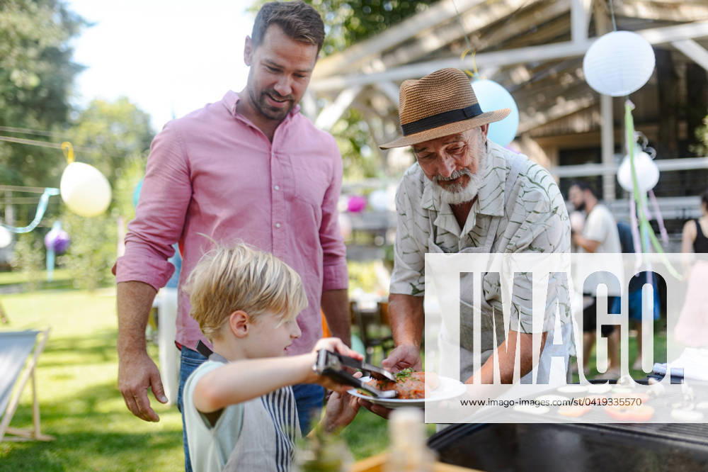 Father, grandfather and son grilling together at garden BBQ. Three generations of men at summer family garden party. Father, grandfather and son grilling together at a garden bbq party. Three generations of men at summer family garden party. model released