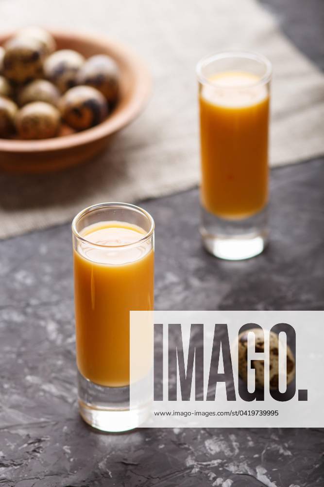 Sweetie Egg liqueur at Glass with Quail eggs at a Black people Concrete background Side view, inconspicuous, Close-up