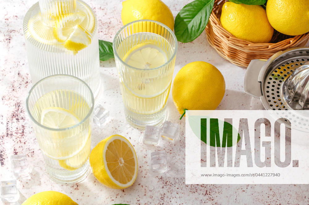 Summer lemon lemonade in a glass and decanter. Lemons are scatte CR_KUAL240313-1366534-01
