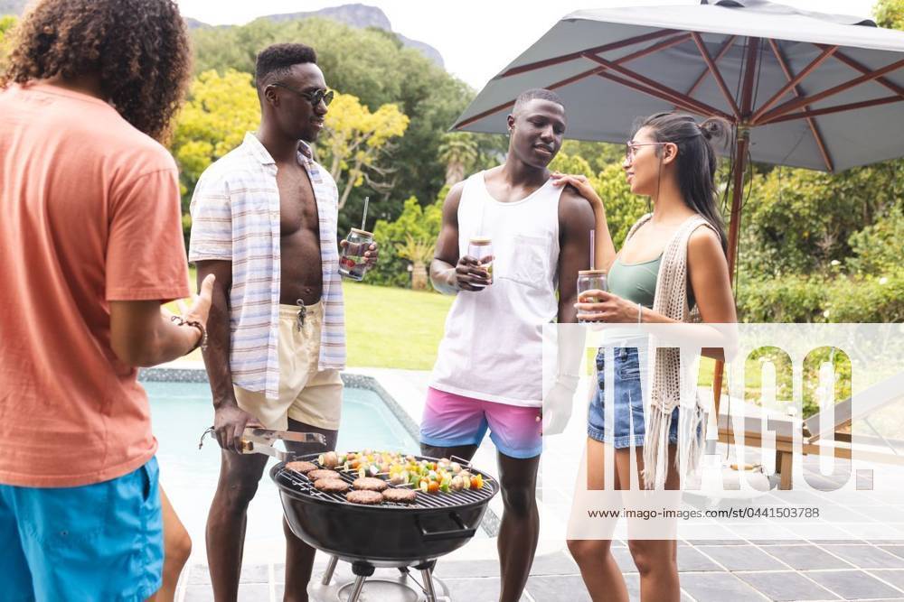 Diverse friends enjoy a barbecue outdoors, with a young African American man at the grill Diverse friends enjoy a barbecue outdoors, with a young African American man at the grill. They are chatting and holding drinks, creating a relaxed and social atmosphere., model released, , property released, Cape Town, South Africa, 15.11.2023, 4951688.jpg, people,diverse friends,barbecue,outdoors,African American,grill,chatting,drinks,relaxed,social atmosphere,friends,gathering,diverse,food,cooking,socializing,happy,happy people,joyful,outdoor activity,leisure,diversity,friendship,relaxation,summer,cookout,happiness,young,men,women,multicultural,unity,fun,picnic,conversation,connection,togetherness,celebration,lunch,dinner,meal,event,community,enter