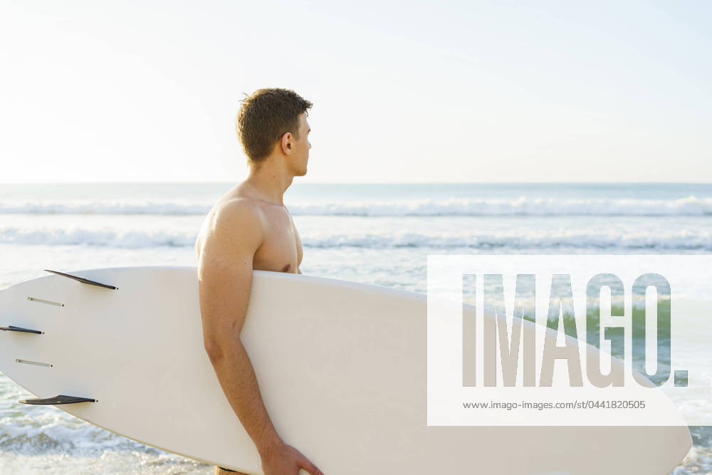 Young man carrying surfboard and looking at sea model released, Symbolfoto, AAZF01671