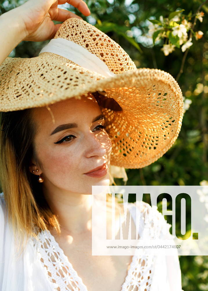 A beautiful woman in a straw hat in a summer blooming garden Gera, Thuringia, Germany CR_GGIE2403224F-1376457-01 ,model released, Symbolfoto