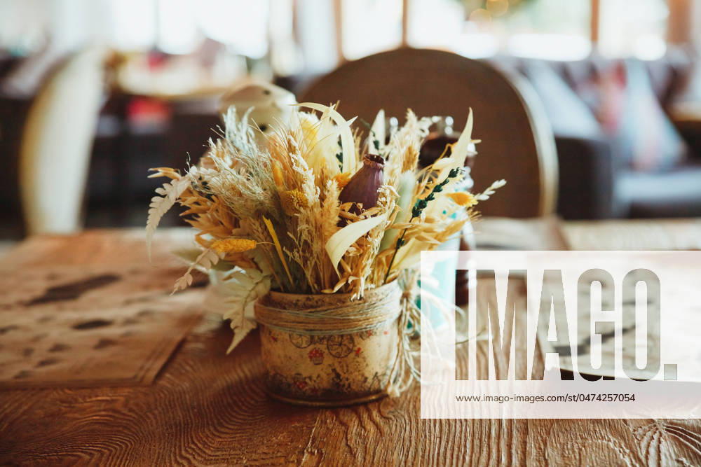Stalks of dry wheat in vase on blurred background. Wheat spikelets. Image for design and interioir.Straws or dry plants.Stylish Eco interior concept. Minimalist interior cafe or coffee house. Stalks of dry wheat in transparent glass vase on white background. Wheat spikelets. Image for design and interioir.