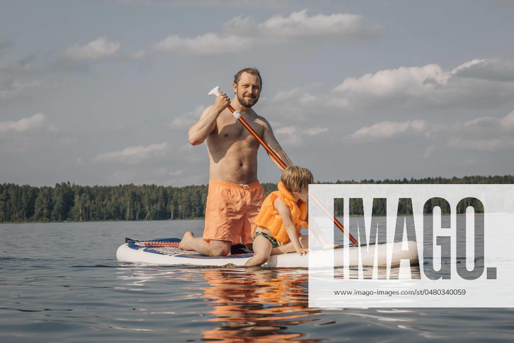 Shirtless man with son on SUP board in sea at sunny day model released, Symbolfoto, EVKF00132