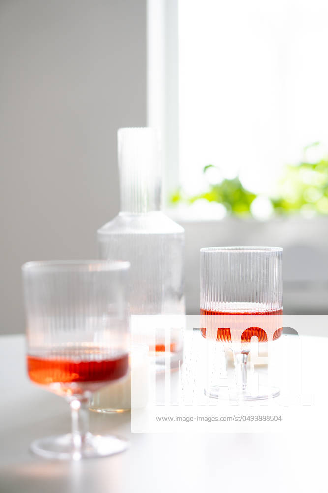 Rose wine in trendy ribbed wineglasses and decanter on white table Rose wine in trendy ribbed wineglasses and decanter on white table, weekend home wine party with candles close-up