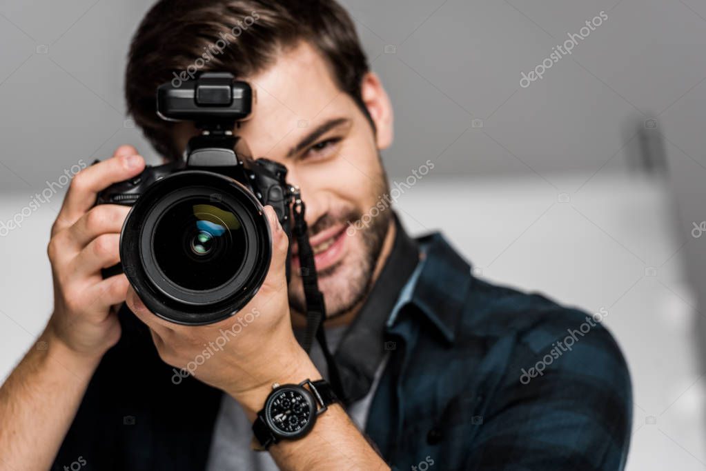 Smiling young man photographing with camera in studio model released