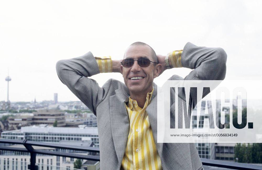 Stephan Remmler (Musiker, Sänger) 09 96 mal Musik Pop Gesang Mann dunkelhaarig kurzhaarig Sonnenbrille Schmuck Ohrring leger Hemd gestreift Jackett draußen stehend Gebäude Stadtansicht Geländer Hand posierend quer halb