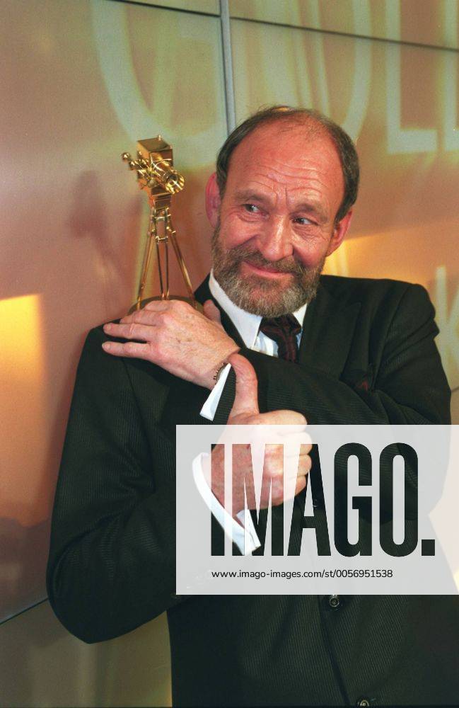 Michael Mendl (Schauspieler) 02 04 urb Mann Schauspiel Schauspieler Film TV Fernsehen grauhaarig kurzhaarig Halbglatze seriös festlich Anzug Krawatte stehend halb hoch lächelnd Saal Bühne Preisträger Trophäe Preis haltend zur Seite schauend Fototermin Verleihung 39. Goldene Kamera am 04.02.2004 im Konzerthaus am Gendarmenmarkt in Berlin