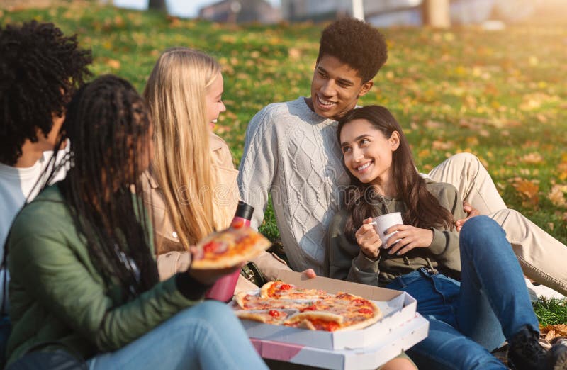 Group of multiracial friends having fun at public park, Group of multiracial happy friends having fun at public park, eating pizza and talking