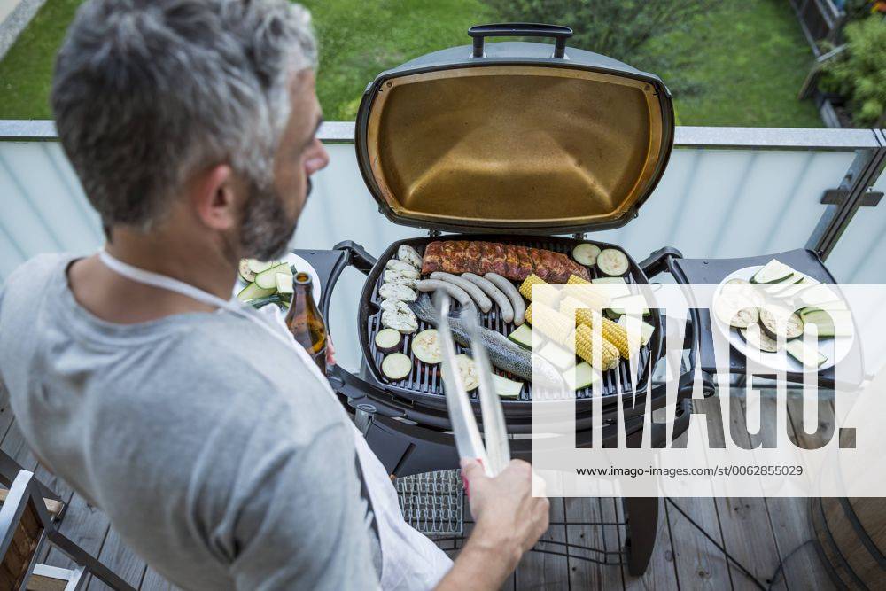 Man barbecuing on his balcony model released Symbolfoto property released MBEF001276