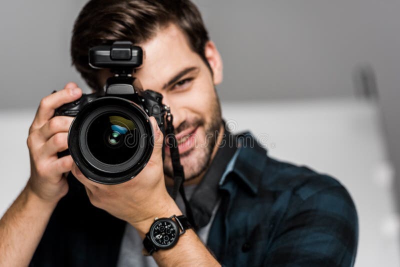 Smiling young man photographing with camera, smiling young man photographing with camera in studio model released