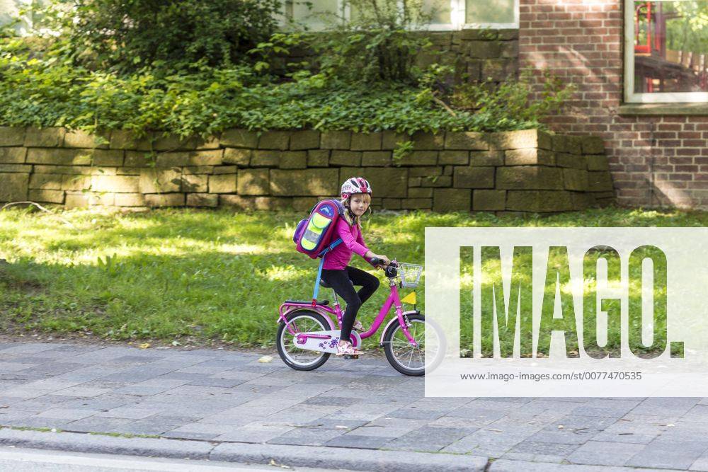 Smiling little girl with school bag riding bicycle on pavement model released Symbolfoto JFEF00838