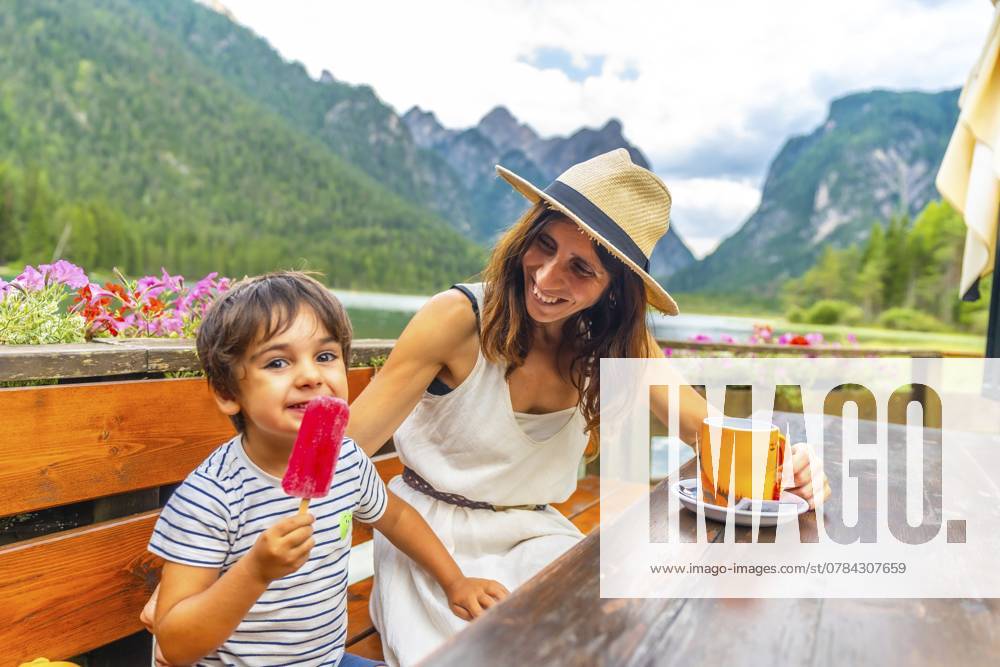 Mutter und Sohn genießen eine Brotzeit am See vor einer malerischen Bergkulisse in den Dolomiten Mother and son enjoying a lakeside snack with a picturesque mountain backdrop in the dolomites