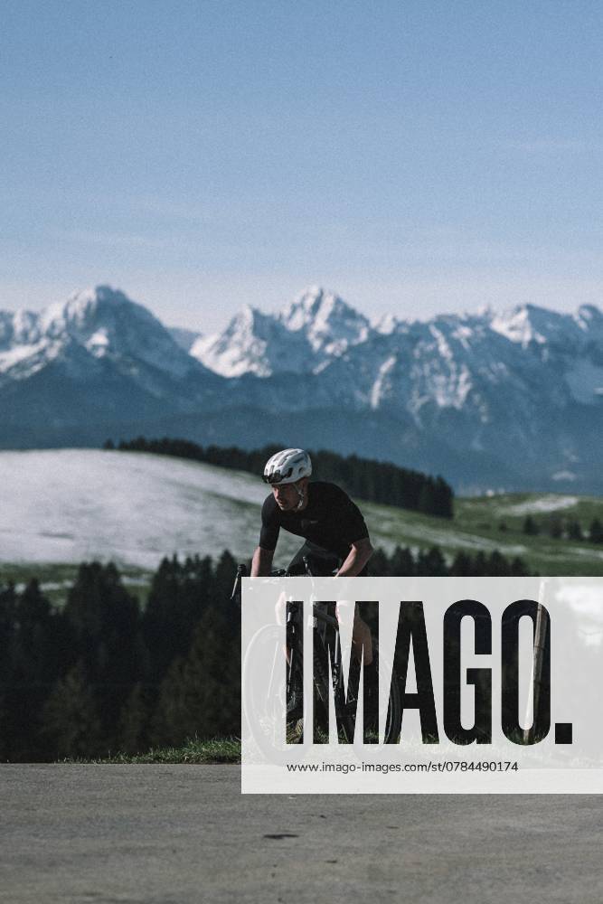 Rennrad Fahrer im Frühling in der Nähe von Halblech im Allgäu vor malerischer Kulisser der Alpen, Bayern, Deutschland, Europa Road bike rider in spring near Halblech in the Allgäu in front of a picturesque backdrop of the Alps, Bavaria, Germany, Europe