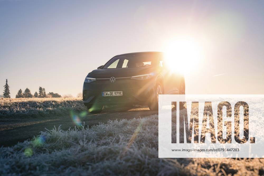 Ein Auto steht auf einem frostigen Feld im Winter, die Sonne scheint intensiv im Hintergrund, Car Sharing, Elektro Auto, Volkswagen ID 5, Gechingen, Hecken und Gäu Region, Schwarzwald, Deutschland, Europa A car parked in a frosty field in winter, the sun shining intensely in the background, car sharing, electric car, Volkswagen ID 5, Gechingen, Hecken und Gäu region, Black Forest, Germany, Europe