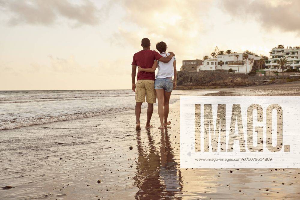 IMAGO Creative: Sommer, Abendspaziergang Spain, Canary Islands, Gran Canaria, back view of couple in love walking on the beach model released Symbolfoto PACF00011