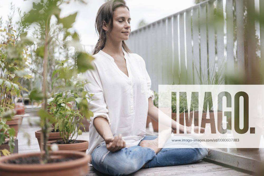 Woman sitting on balcony practicing yoga model released Symbolfoto property released JOSF01640