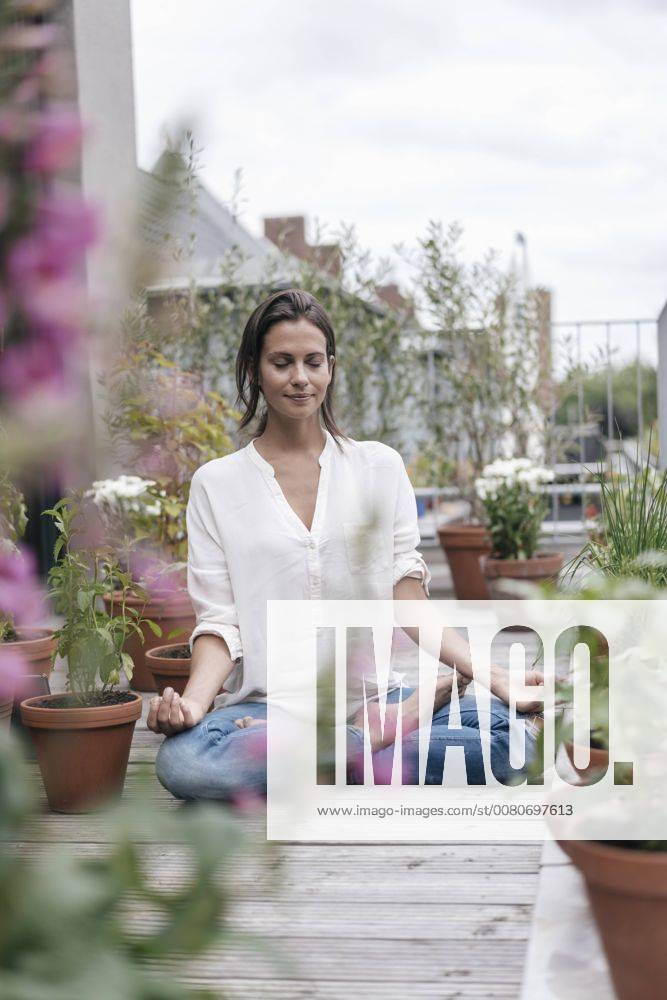 Woman sitting on balcony practicing yoga model released Symbolfoto property released JOSF01641