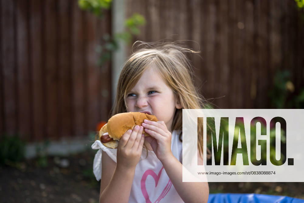 IMAGO Creative, Lifestyle, Feste im Garten #2 Child eating hot dog outdoors in summer garden barbecue party model released, Symbolfoto property released, IGEF00072