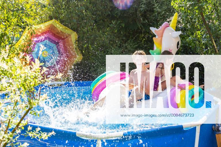 Brother and sister with oversized unicorn swim toy in paddling pool model released Symbolfoto SARF03778