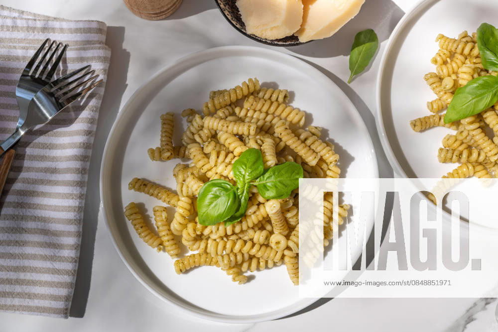 Penne pasta with fresh basil pesto garnished beautifully Delicious plates of penne pasta tossed in a vibrant basil pesto sauce. The dish is garnished with fresh basil leaves, offering a tempting and aromatic Italian meal. Model Released AnnaFedorovaPhoto_ID33124_1126940_003