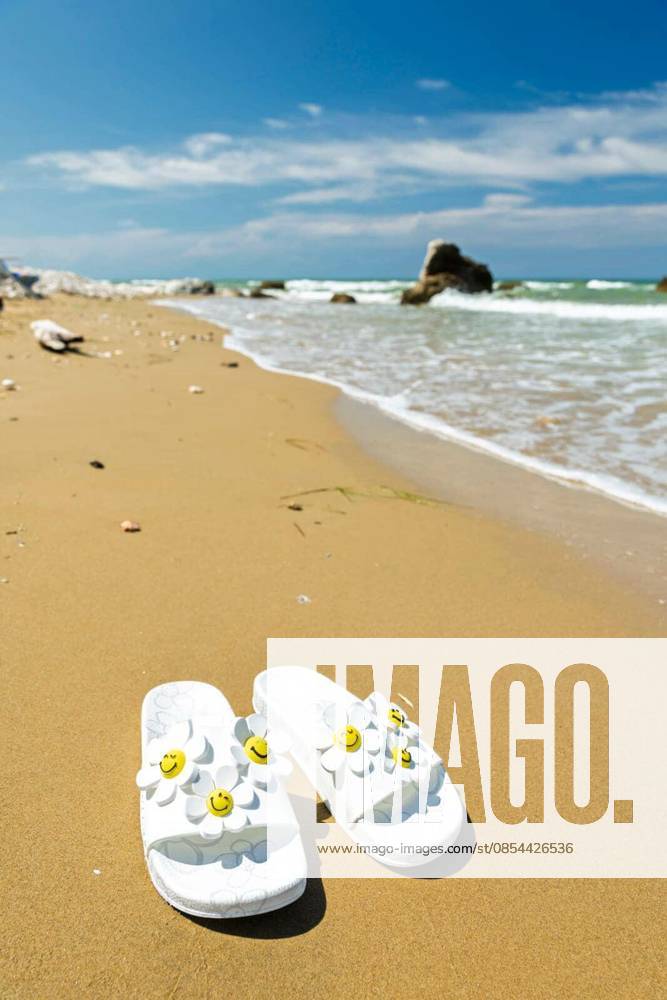White slide sandals on a sunny beach, representing summer vacation and relaxation