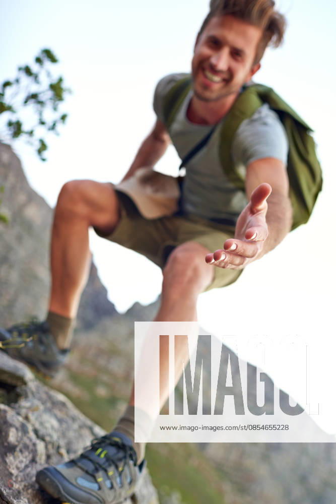 Lending a hand. a handsome young man offering you a hand up the mountain (License=RF) ,model released, Symbolfoto