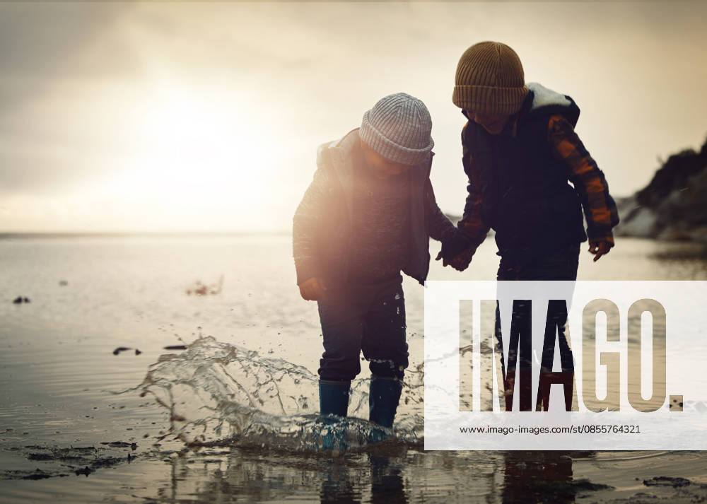 Beach, sunset and silhouette of children in water splash together, holding hands and playing in waves. Fun, holiday and brothers, happy in boots on ocean vacation, jumping in sea on winter evening (License=RF) ,model released, Symbolfoto