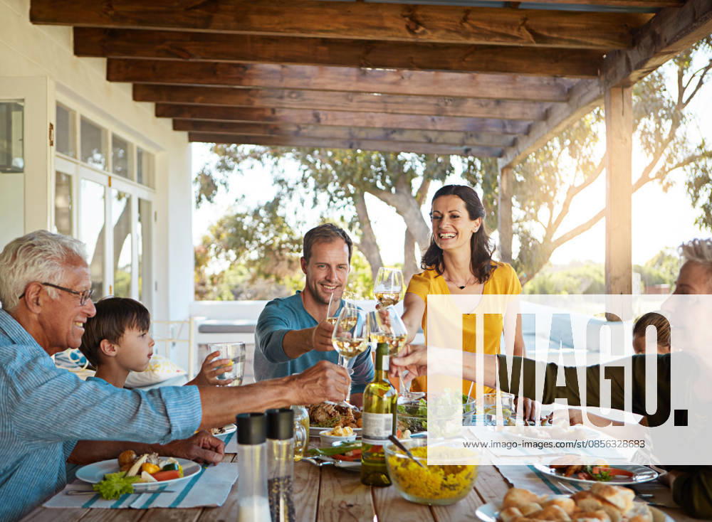 Cheers, wine and happy family in backyard for lunch celebration, eating and bonding together at table. Children, men and women toast with glass, drinks and food on patio for holiday, fun and relax. (License=RF) ,model released, Symbolfoto